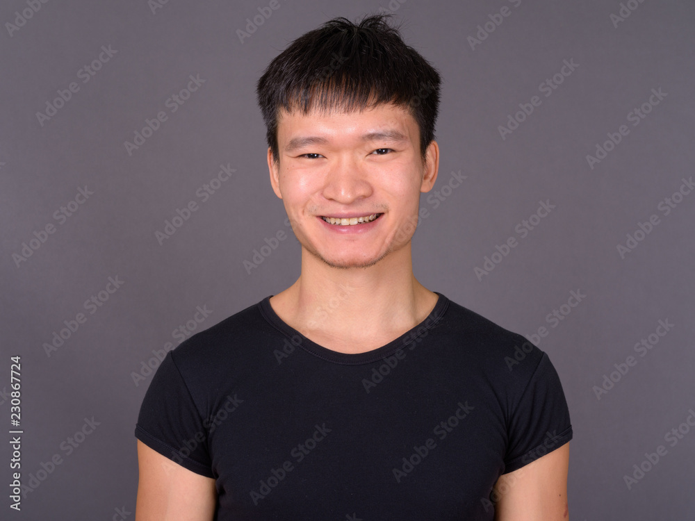 Studio shot of young Chinese man against gray background Studio shot of young Chinese man against gray background