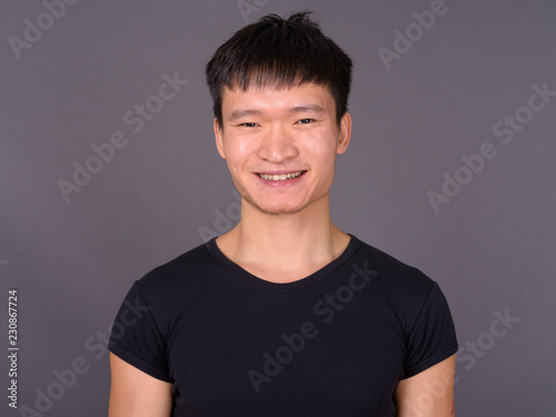 Studio shot of young Chinese man against gray background