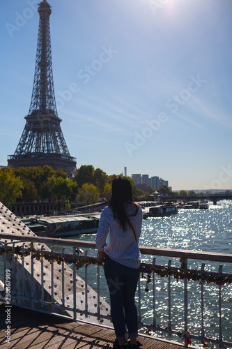 the girl looks at the Eiffel tower from the bridge