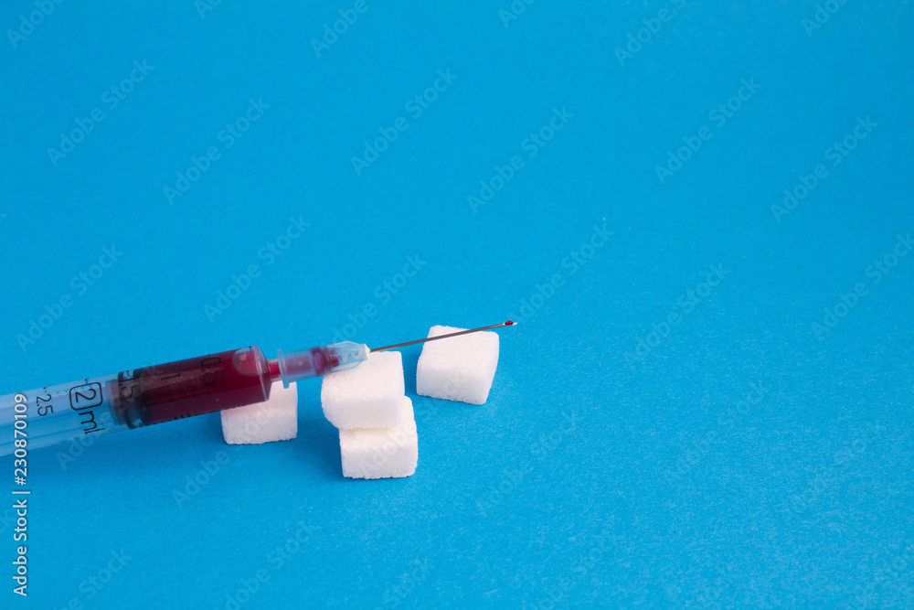 Syringe with blood and sugar on the blue background.Copy space. Syringe with blood and sugar on the blue background.Copy space.