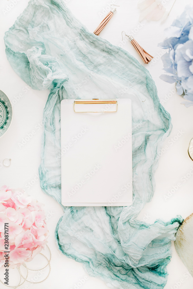 Home office desk with clipboard with copy space, turquoise blanket, colorful pastel hydrangea flower bouquet, woman fashion accessories on white background. Flat lay, top view workspace mockup. Home office desk with clipboard with copy space, turquoise blanket, colorful pastel hydrangea flower bouquet, woman fashion accessories on white background. Flat lay, top view workspace mockup.