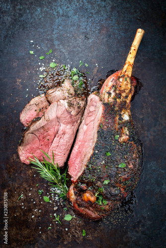 Traditional barbecue leg of lamb sliced with spice and herb as top view on a metal sheet