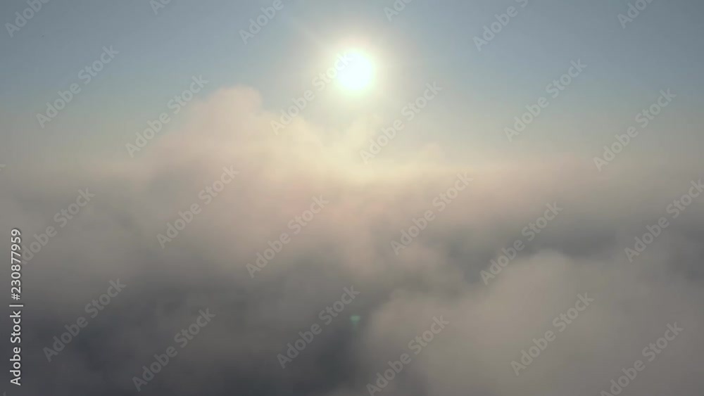 Aerial view over the clouds and sun is shining. Drone flying forward and through while clouds moving. Sun centered above Aerial view over the clouds and sun is shining. Drone flying forward and through while clouds moving. Sun centered above