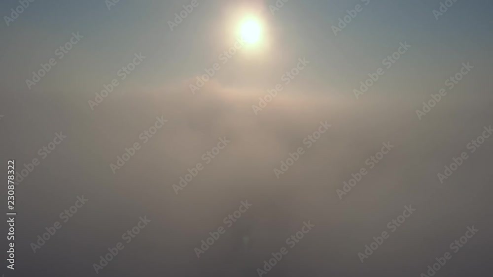 Aerial view over the clouds and sun is shining. Drone flying forward and through while clouds moving. Sun centered above Aerial view over the clouds and sun is shining. Drone flying forward and through while clouds moving. Sun centered above