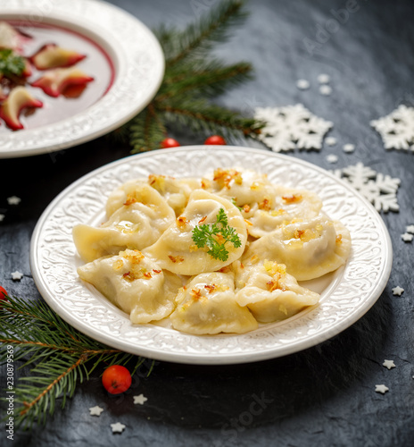 Christmas dumplings stuffed with  mushroom and cabbage on a white plate on a dark background. Vegetarian food, Traditional Christmas eve dish in Poland