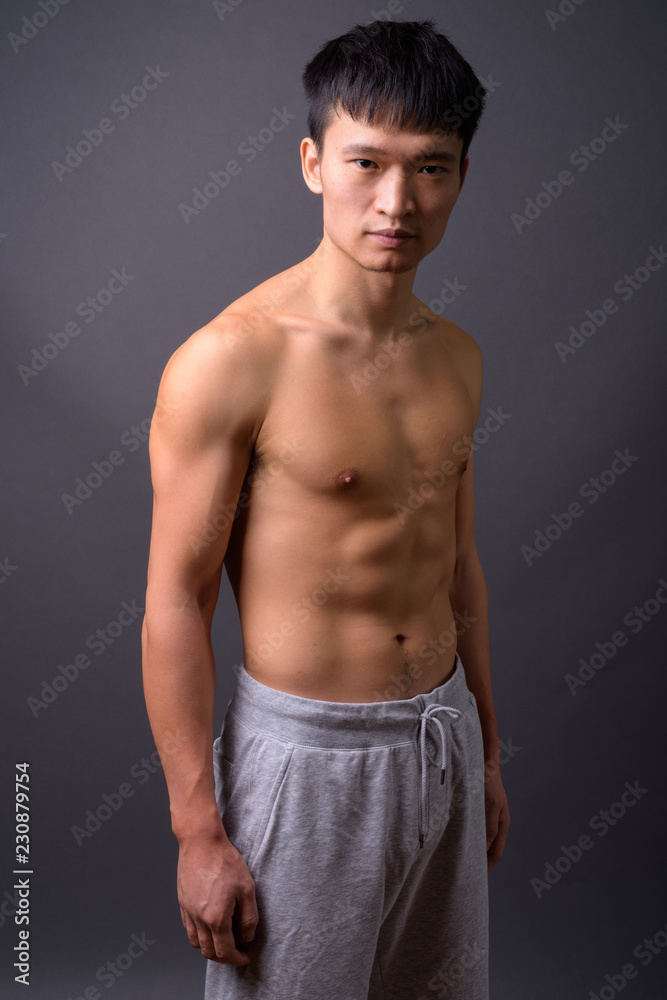 Young shirtless Chinese man against gray background Stock Photo | Adobe ...