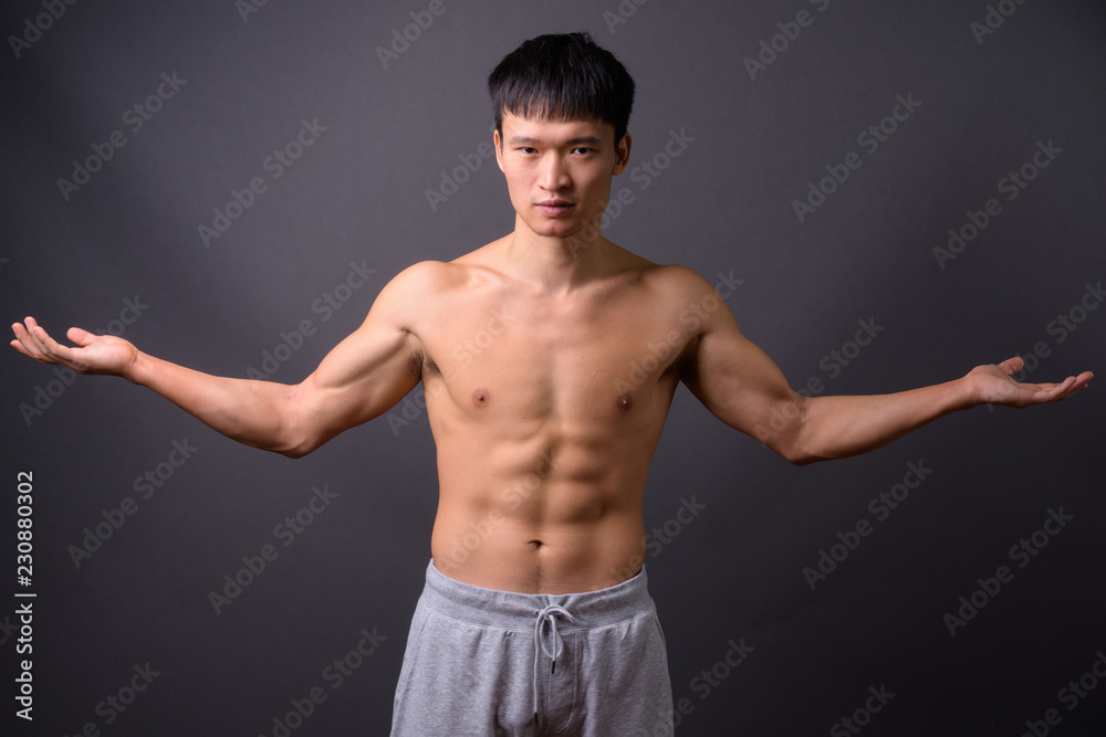 Young shirtless Chinese man against gray background