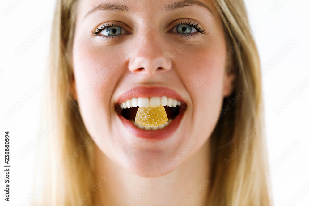 Beautiful young woman with a sweet candy in mouth looking at camera over white background. Beautiful young woman with a sweet candy in mouth looking at camera over white background.