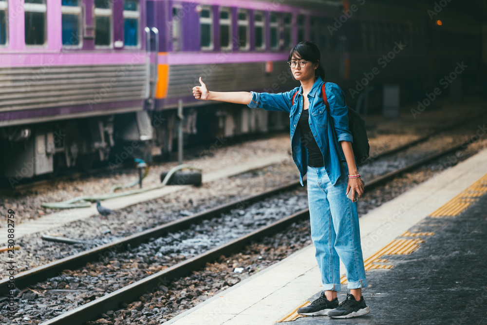 Asian woman traveler waiting train on the platform of the railway station- travel and transportation concept