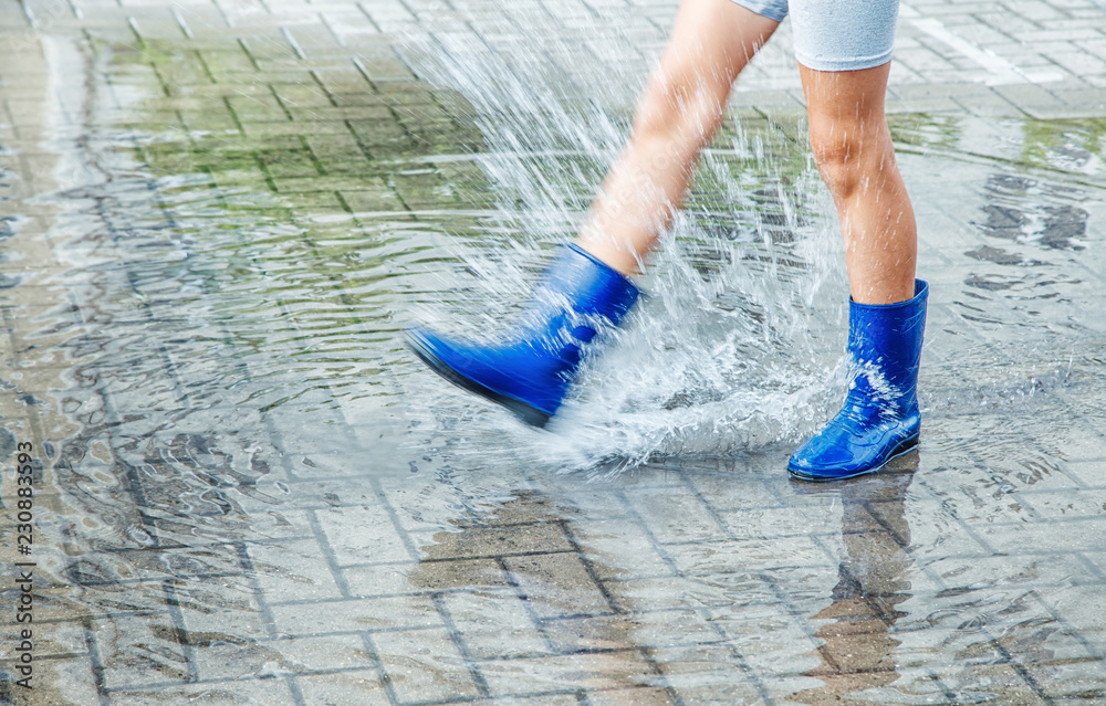 girl in blue rubber boots jumping in a puddle after a rain girl in blue rubber boots jumping in a puddle after a rain