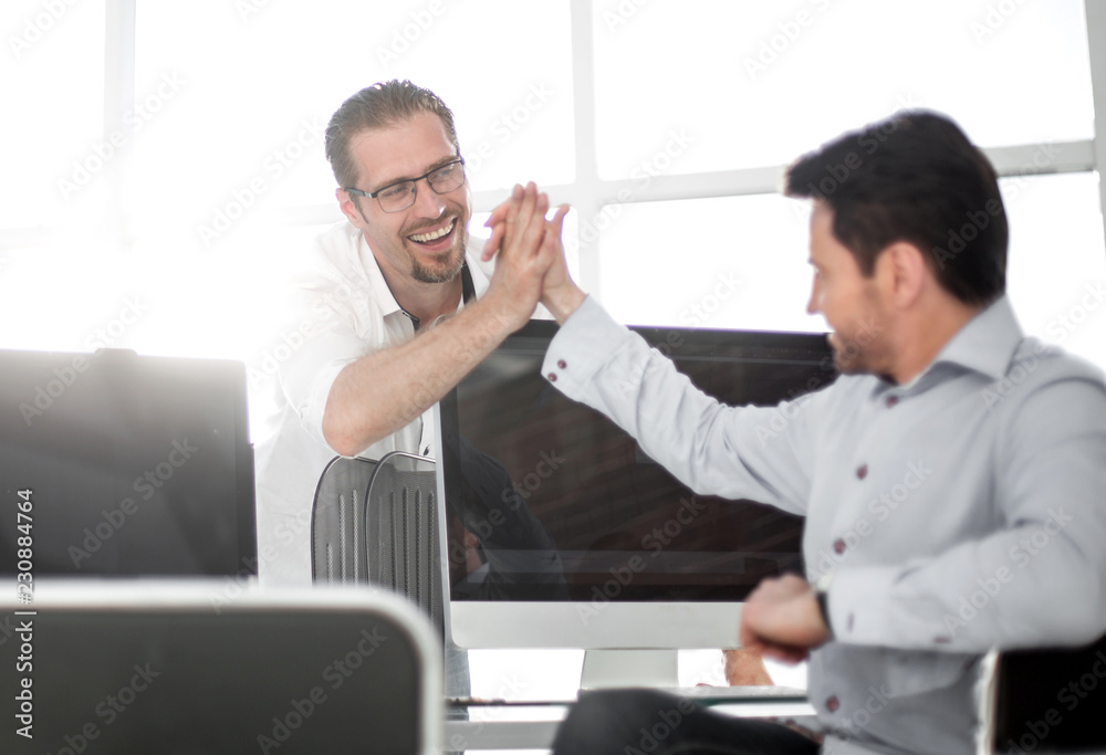 employees give each other a high five over the computer Desk employees give each other a high five over the computer Desk