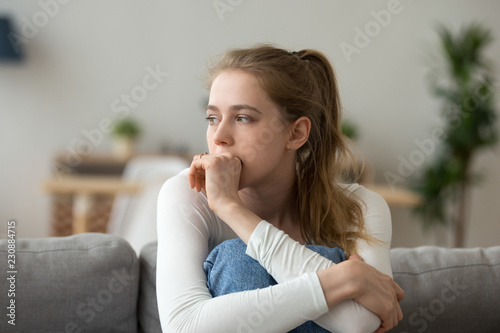 Head shot woman anxious worried woman sitting on couch at home. Frustrated confused female feels unhappy, problems in personal life, quarrel break up with boyfriend and unexpected pregnancy concept photo