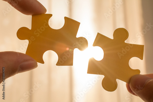 two hands trying to connect couple puzzle piece with sunset background. business strategy concept
