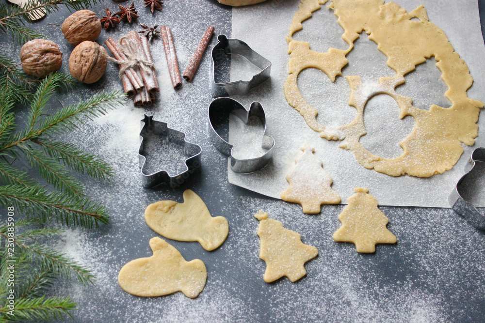 Christmas cookies. Cutting gingerbread. The process of baking cookies at home. Gingerbread dough for cookies, cookies, cinnamon sticks, orange and fir branches. New year or winter holidays still life,