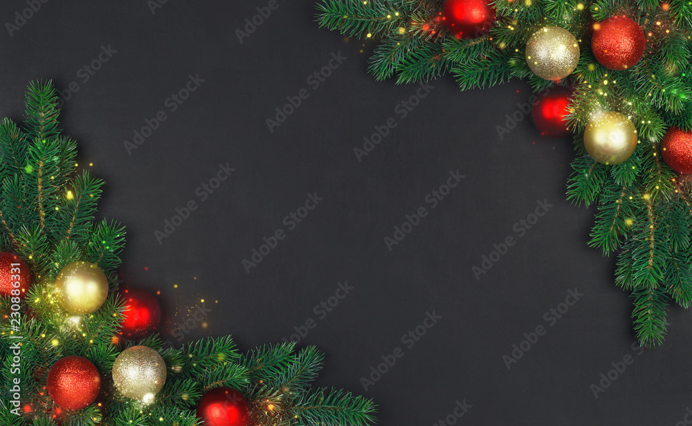 The branch of a Christmas tree with xmas decorations and magical stardust on a black background The branch of a Christmas tree with xmas decorations and magical stardust on a black background