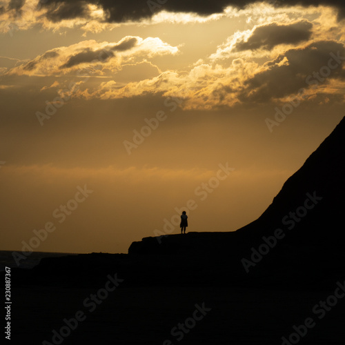 silhouette of woman during sunset next to the sea