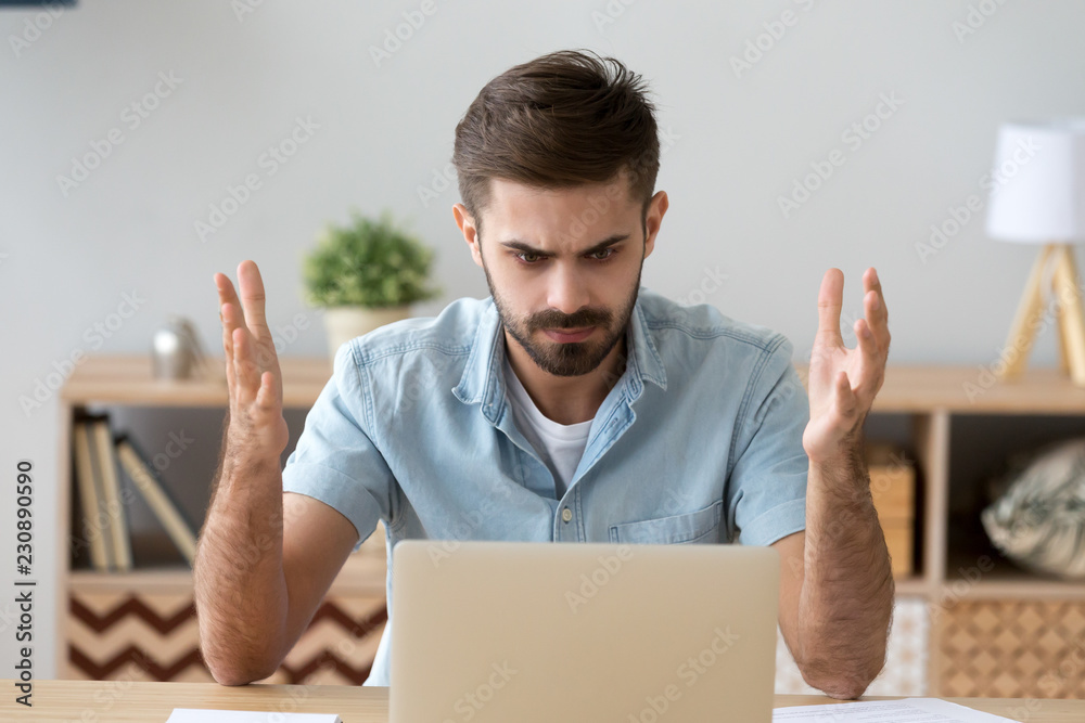 Frustrated annoying man sitting at the desk in office using computer, looking at broken crashed laptop feels anger and indignance. Worried male has verification password problems or data loss concept Frustrated annoying man sitting at the desk in office using computer, looking at broken crashed laptop feels anger and indignance. Worried male has verification password problems or data loss concept