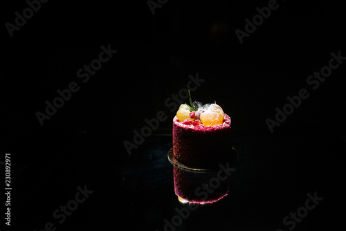 Tasty red cake with fruit on a black background