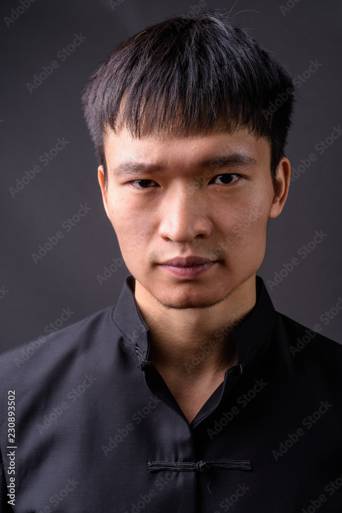 Obraz premium Studio shot of young Chinese man against gray background