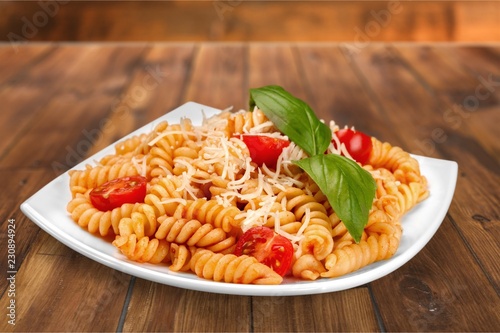 A baked dish of fusilli or pasta spirals, with cherry tomatoes photo