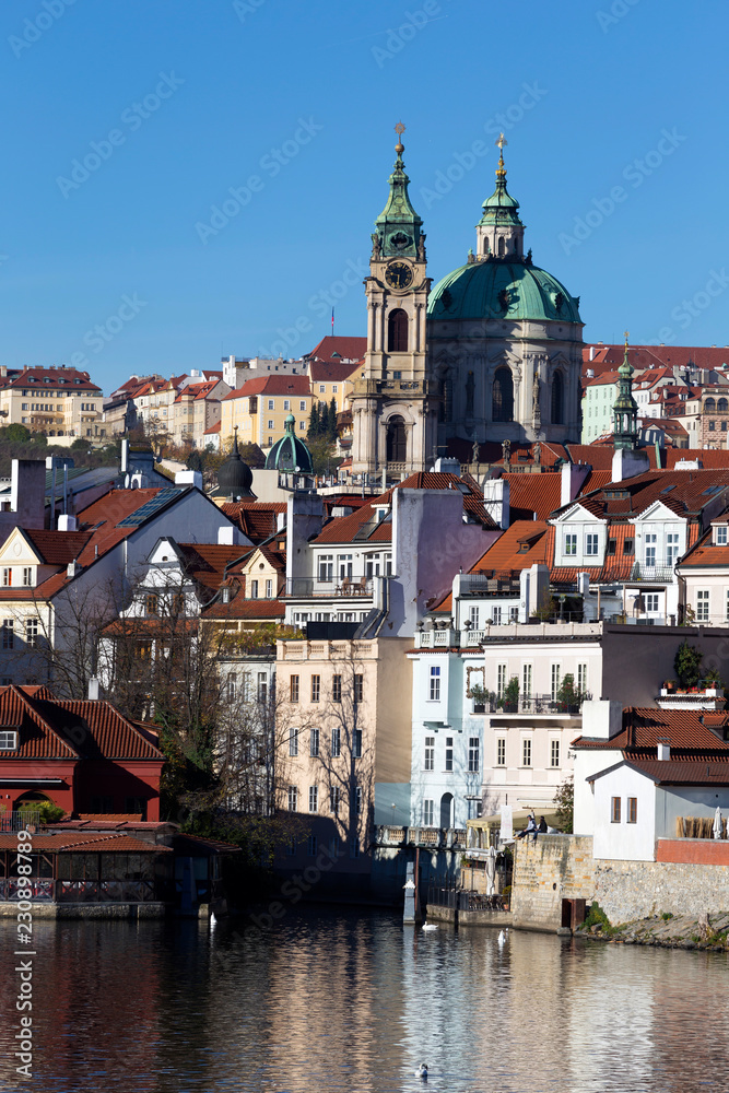 Fototapeta premium Colorful autumn Prague St. Nicholas' Cathedral with the Lesser Town above River Vltava in the sunny Day, Czech Republic