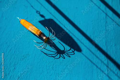 light and shadow of old squid lure on blue wood floor photo