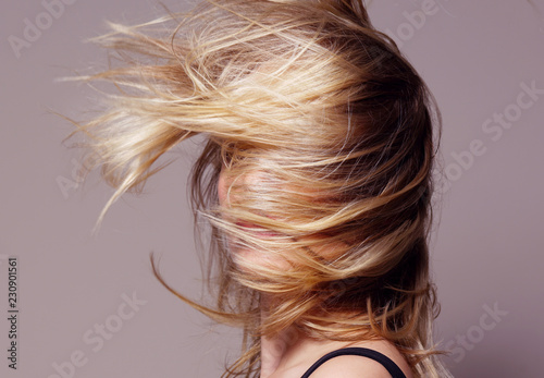 beauty portrait of attractive young caucasian woman blond on beije background studio shot hair wind blowing