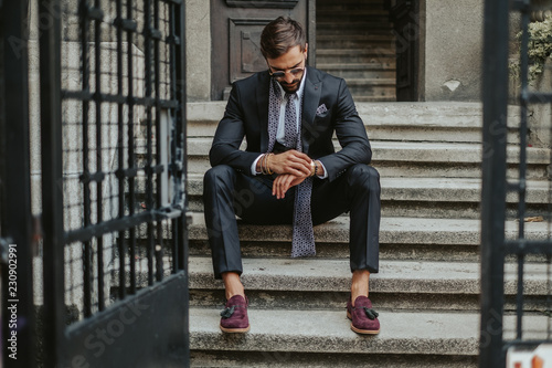 Businessman waiting on the stairs and looking at the time photo