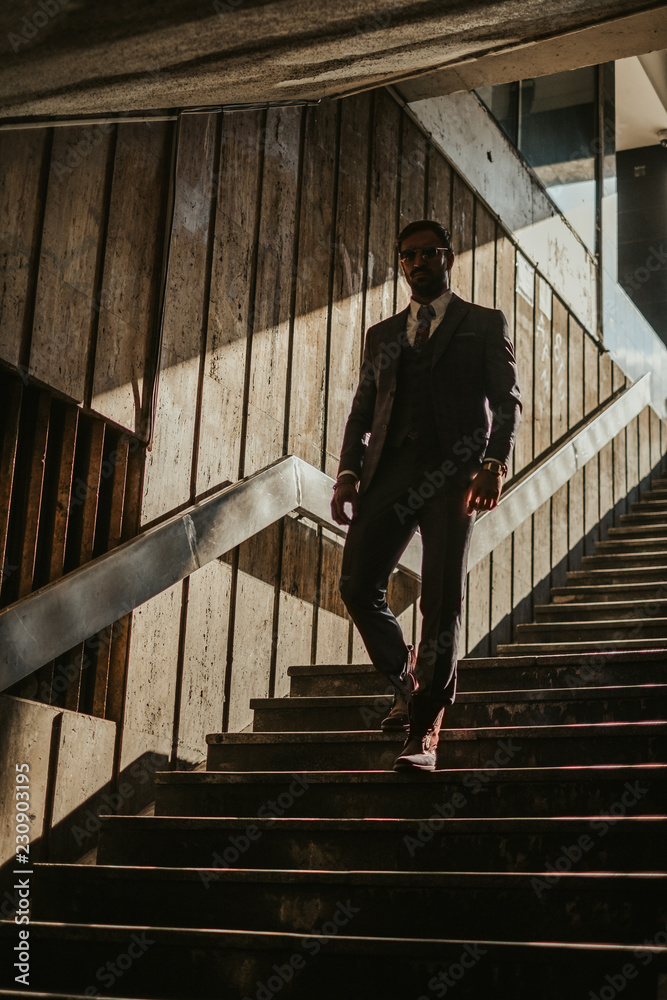 Businessman with sunglasses walking down the stairs Businessman with sunglasses walking down the stairs