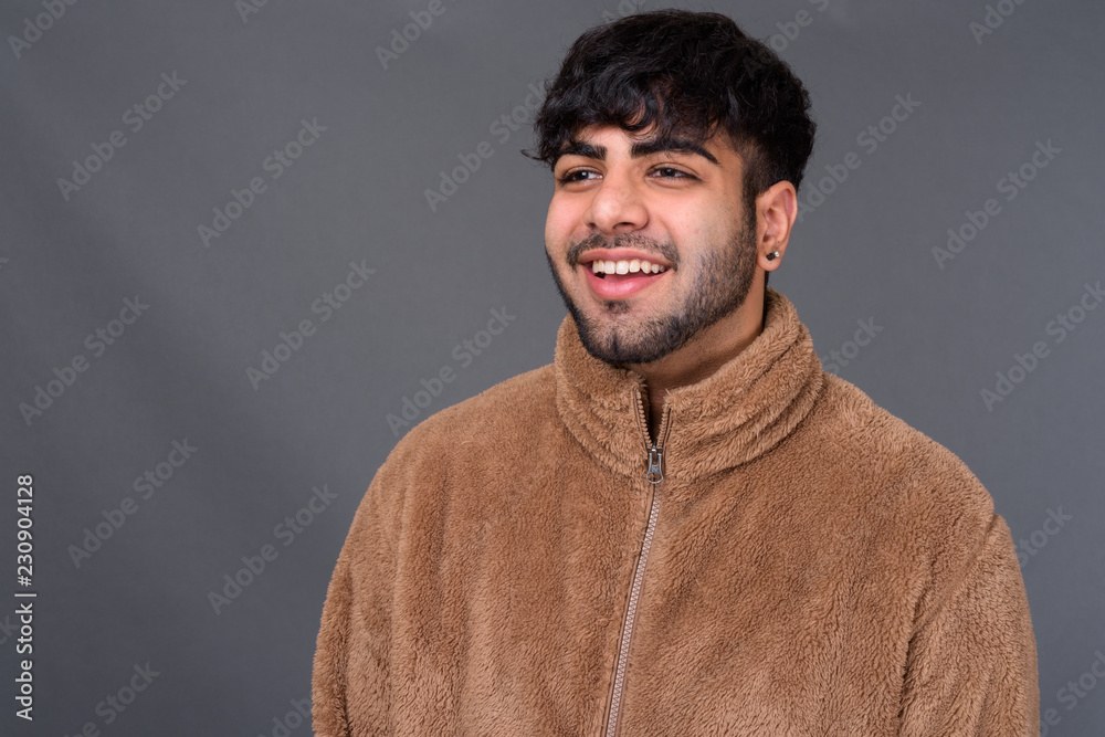 Young handsome Indian man against gray background