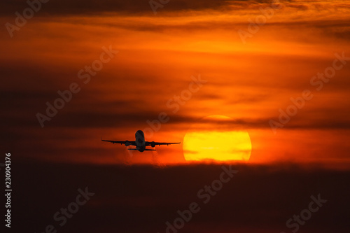 Air plane taking off at sunset near to the sun with beautiful red cloud in background