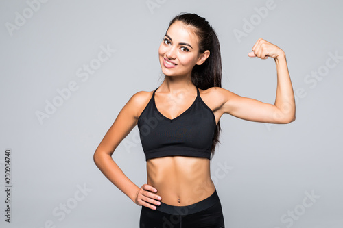 Cheerfully smiling fitness sporty woman demonstrating biceps isolated on white background