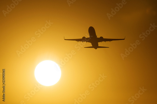 Silhouette of an air plane near to the sun with beautiful red clouds in background © danmir12