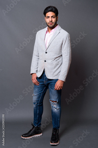 Young handsome Indian businessman against gray background