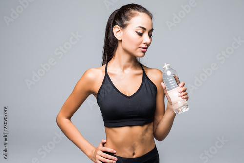 Cheerful attractive young fitness woman posing with bottle of water over white background © F8 \ Suport Ukraine