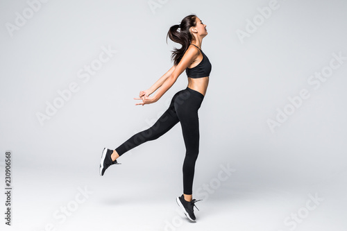 Full length of jumping fitness woman over gray background