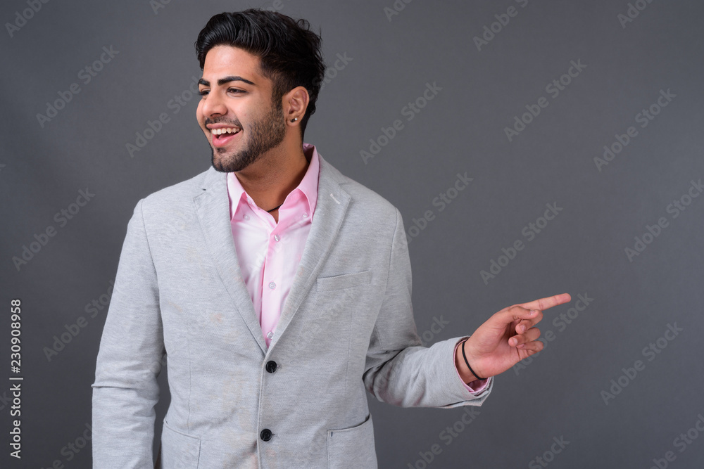 Young handsome Indian businessman against gray background Young handsome Indian businessman against gray background