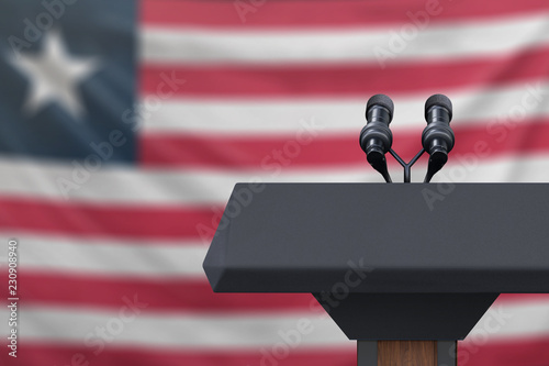 Podium lectern with two microphones and Liberia flag in background photo