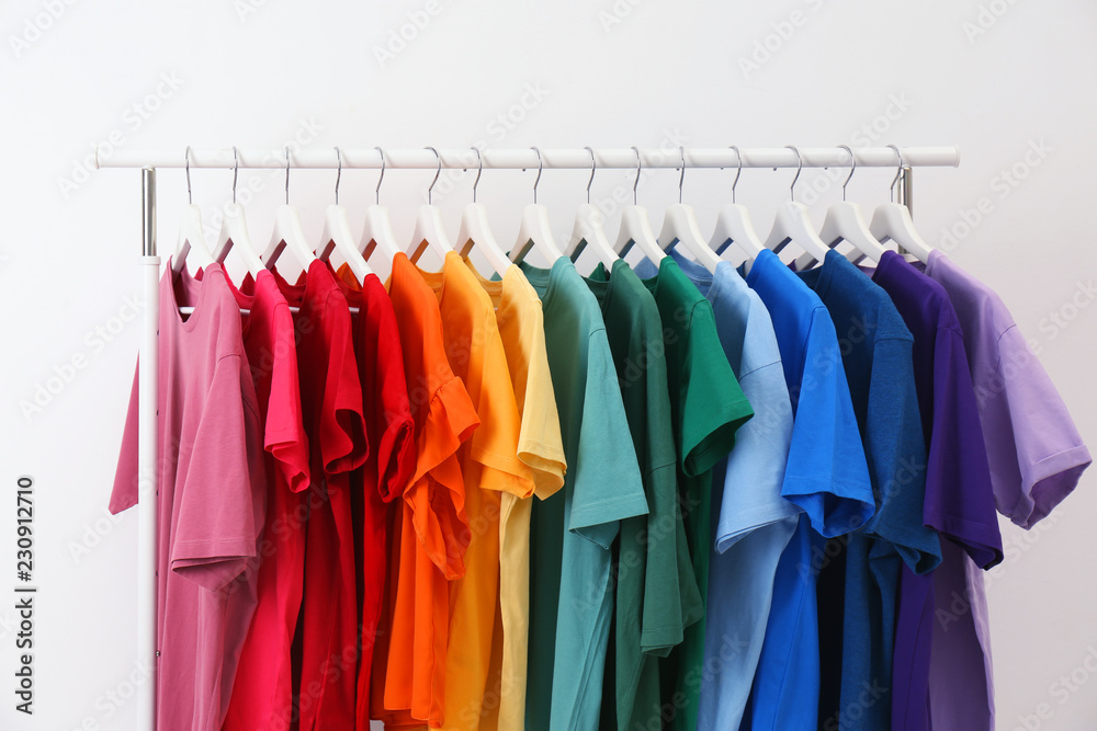 Rack with bright clothes on white background. Rainbow colors Rack with bright clothes on white background. Rainbow colors
