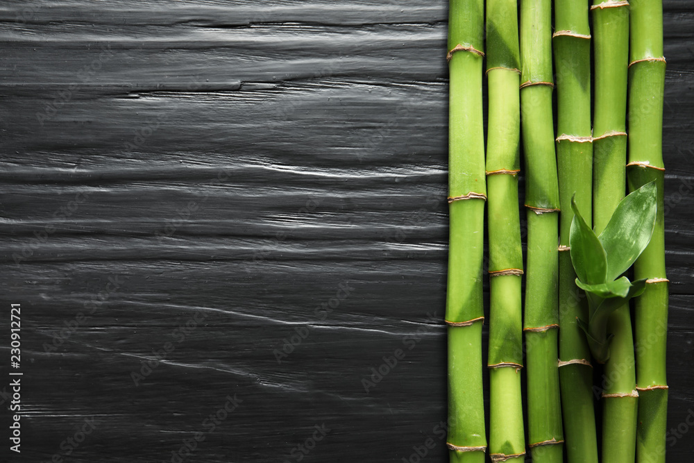 Fototapeta premium Green bamboo stems and space for text on wooden background, top view