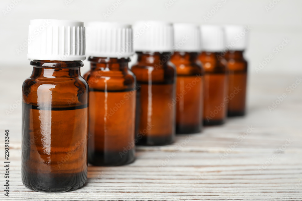 Glass bottles with essential oil on wooden table Glass bottles with essential oil on wooden table