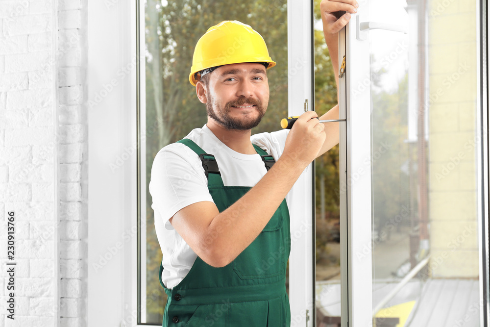 Construction worker installing new window in house Construction worker installing new window in house