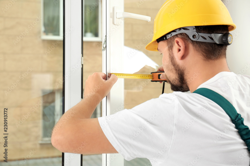 Construction worker installing new window in house Construction worker installing new window in house