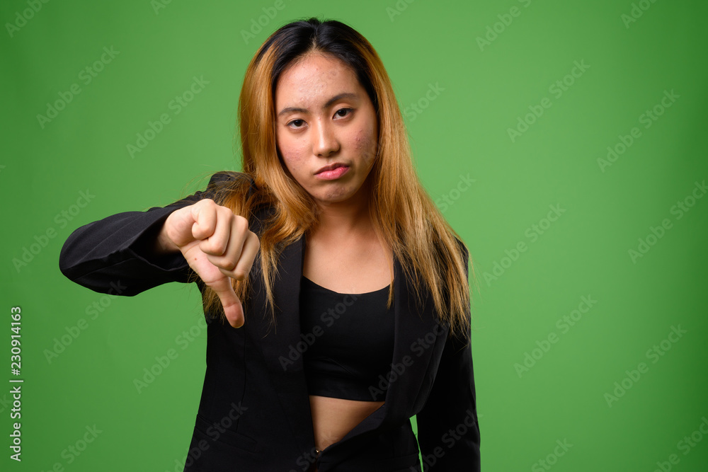 Portrait of young Asian businesswoman against green background Portrait of young Asian businesswoman against green background