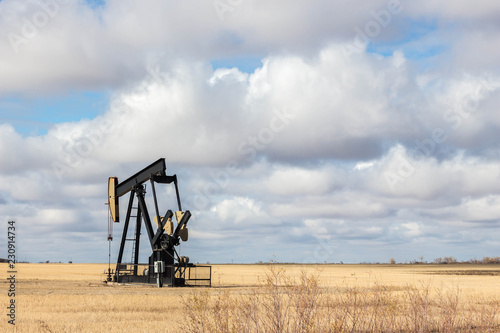 oil well sitting in a golden field under blue sky