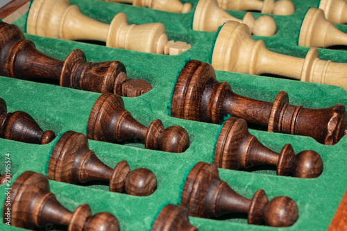 wooden chess pieces (white / black) are neatly folded in a box with a green background