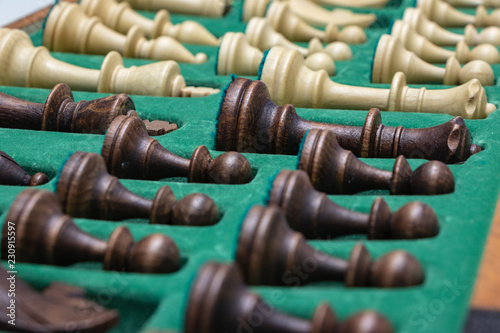 wooden chess pieces (white / black) are neatly folded in a box with a green background