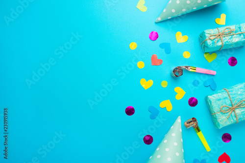 Birthday caps, blowers and confetti on a bright background