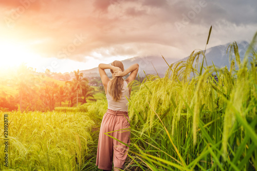 Young woman traveler on Beautiful Jatiluwih Rice Terraces against the background of famous volcanoes in Bali, Indonesia with sunlight photo