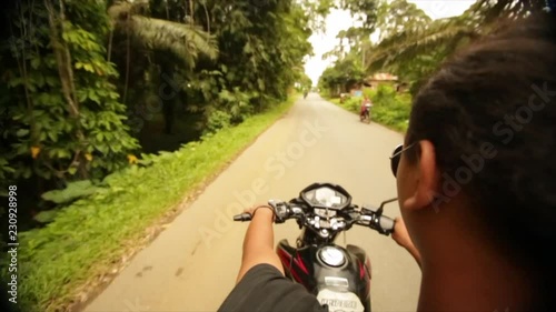 Man rides motorbike through rural palm fields in Indonesia